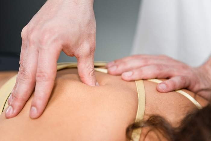 Woman probing back for trigger points to massage
